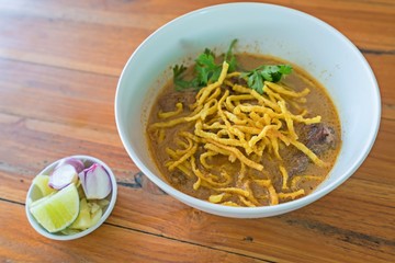 Thai Northern style curry soup with yellow noodle, beef and side dish on wood table.
Thai Food call 