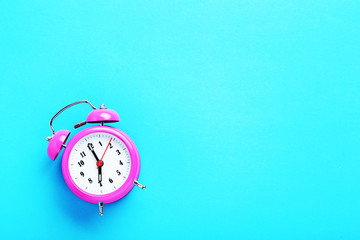 Pink alarm clock on the mint background