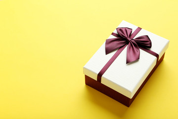 Gift box with ribbon on yellow background