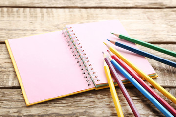 Drawing colourful pencils with notebook on brown wooden table