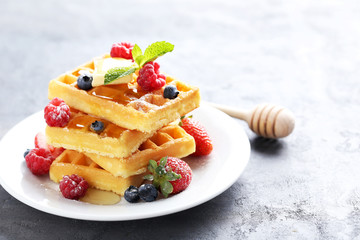 Homemade waffles with berries in plate on grey table