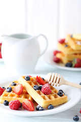 Homemade waffles with berries in plate on blue wooden table