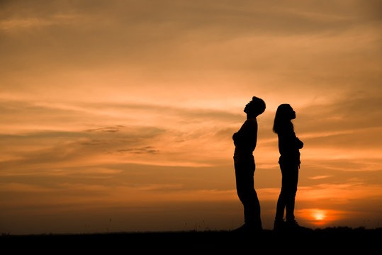 Silhouette of couples who are quarreling (standing back to back),anger and have something problems with sunset background in Thailand,anger and bad relationship concept.