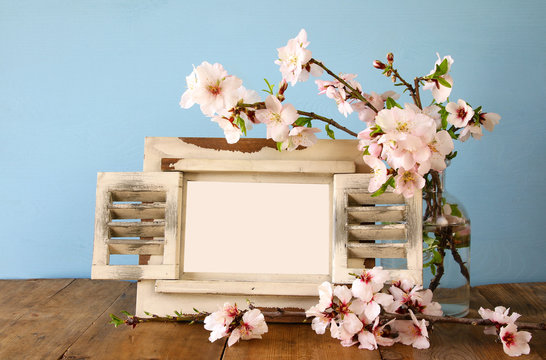 Vintage blank photo frame next to spring flowers