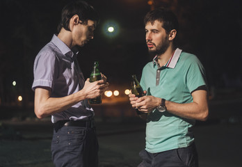 Young men drinking beer outdoors at night