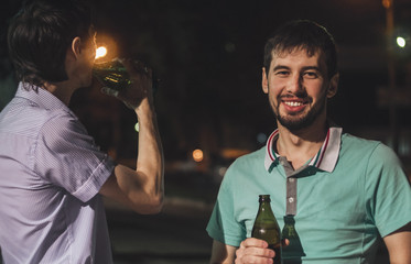 Young men drinking beer outdoors at night