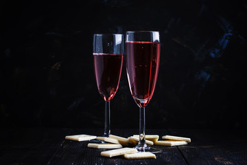 Rose sparkling wine in glasses and white chocolate, dark background, selective focus