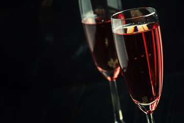 Rose sparkling wine in glasses and white chocolate, dark background, selective focus
