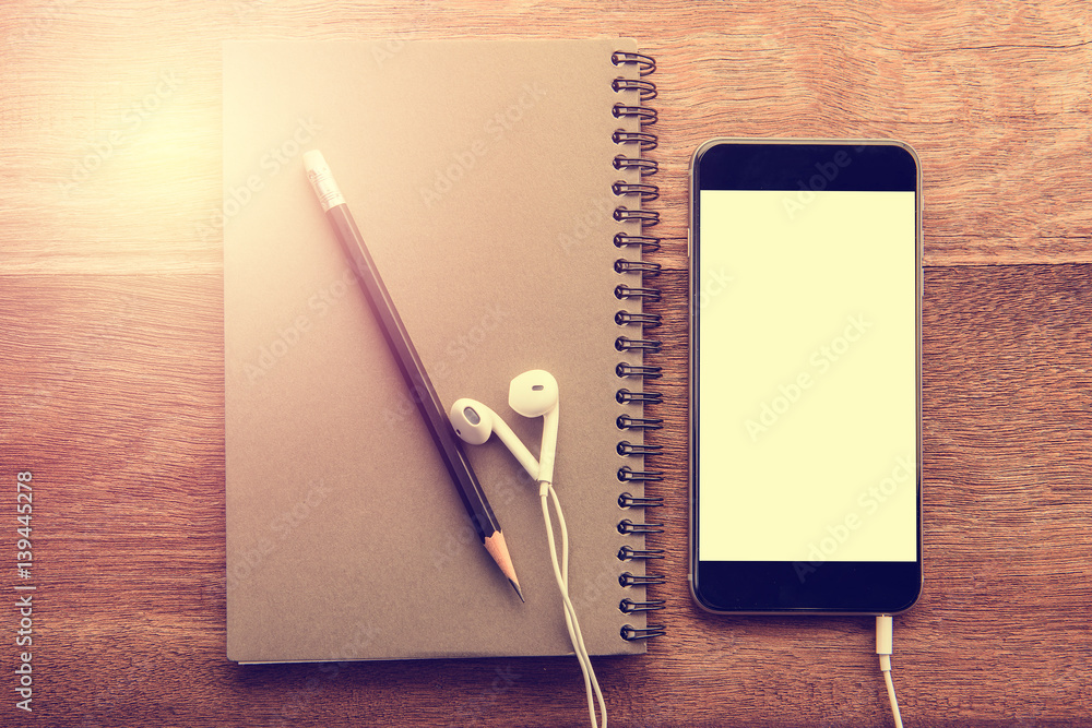 Aufkleber Smartphone with white screen and Note book On Wooden Table With Copyspace