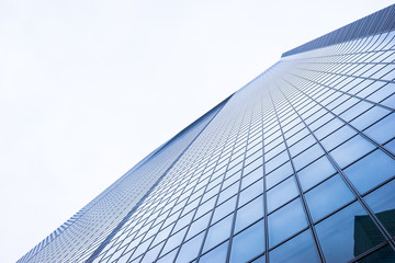 Business concept for real estate and corporate construction - looking up view in financial district, the silhouettes of skyscrapers city reflect dramatic blue sky, sun lights in Tokyo, Japan