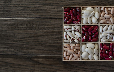 Assortment of beans in wooden box on  wooden background 