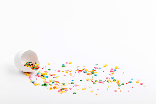 Egg Shell Colorful Sugar Sprinkle Dots On White Table With Copy Space. Easter Concept