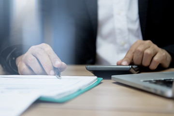 Close up of people working with graph and laptop on his wooden table in the office on business concept