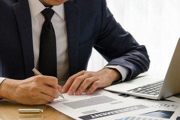 Close up business man signing agreement contract making a deal. (classic business concept to make decision with document and notebook)