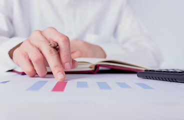 business and financial document  on the table with people using calculator and writing on notebook