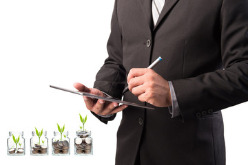 Business man working with a digital tablet with money in clear bottle on white background,investment concept