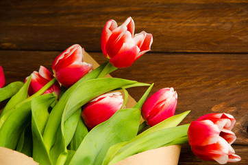 Bouquet of tulips in kraft paper. red white tulips on wooden boards.