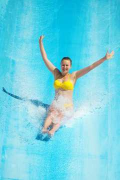 Woman sliding down on water-slide in aqua park.