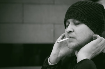 Portrait of a man with a beard with a mustache, smoking a cigarette, with an emotional face in the open air