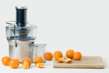 Modern electric juicer and fresh oranges, white background with copy space