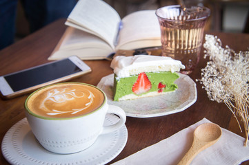 coffee cup and tasty cake relax time book and mobile phone on table in coffee shop