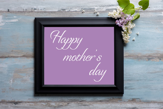 Picture frame with lilac flowers and Happy Mother's day message on blue wooden background
