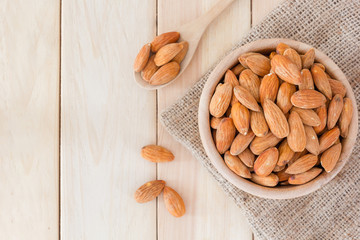 Almonds nut in wooden bowl on wooden table, Top view with copy space and text.