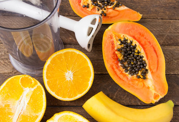 Orange, papaya and banana on a wooden table.