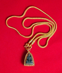 Gold necklace 96.5 percent Thai gold grade with Buddha and gold frame pendant isolated on red flannel cloth background