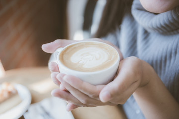 Fototapeta na wymiar woman hand holding a cup of hot latte art