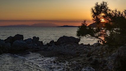 Obraz premium Evening on orange sunset on the sea coast in the summer among the rocks.