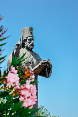 Statue of orthodox catholic priest and flowers in Podgorica, Montenegro