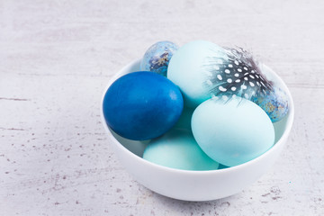 Plate with painted dark and light blue eggs on wooden table desktop