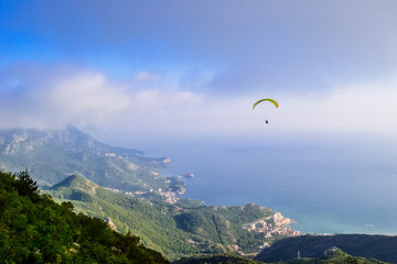 Man paragliding over Budva mountains overseeing sunny seaside