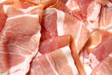 Prosciutto crudo a fette affettato e servito su di un piatto bianco