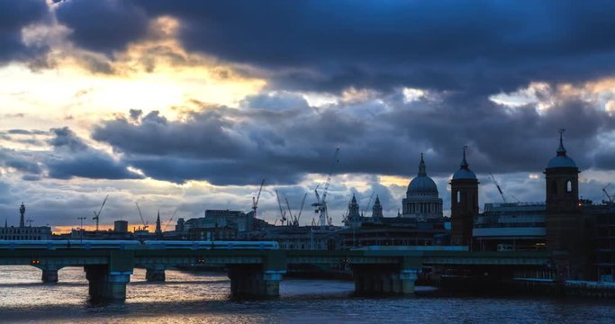 Cannon Street Station with train bridge in London at sunset during the Summer of 2016.
Blue clouds and yellow sun reflects on the River Thames.