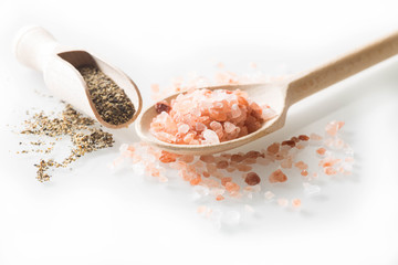 Fototapeta na wymiar Himalayan salt and pepper on wooden spoon on a white background.