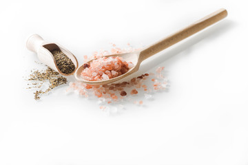 Himalayan salt and pepper on wooden spoon on a white background.