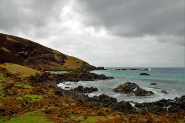 Long shot of the Ovahe beach, a small cove surrounded by red cliffs in Easter Island, Rapa Nui,...