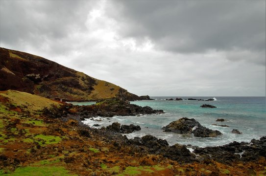 Long shot of the Ovahe beach, a small cove surrounded by red cliffs in Easter Island, Rapa Nui, Chile, South America