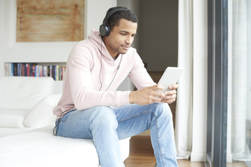 Obraz premium Enjoy music. Young African American man listening music on digital tablet