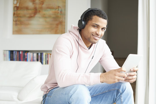 Enjoy music. Young African American man listening music on digital tablet