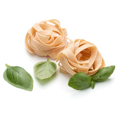 Italian pasta fettuccine nest and basil leaves  isolated on white background cutout