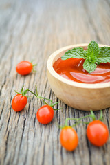 tomato sauce in a bowl and fresh tomatoes on old wood