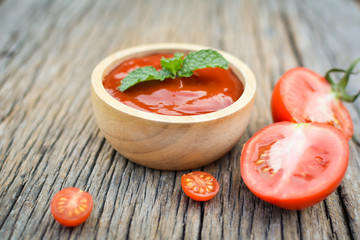 tomato sauce in a bowl and fresh tomatoes on old wood