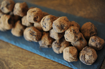 Chocolate truffles in cocoa sprinkled. On the slate board on wooden background. Close-up, texture