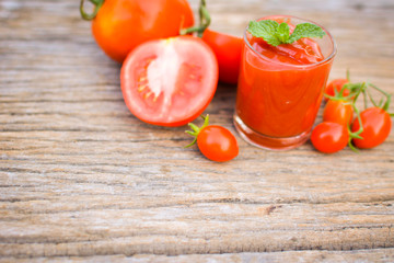 tomato sauce in a glass and fresh tomatoes on old wood