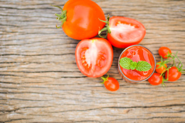 tomato sauce in a glass and fresh tomatoes on old wood