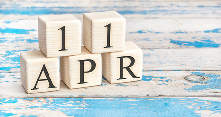 April 11th. Wooden cubes with date of 11 April  on old blue wooden background.