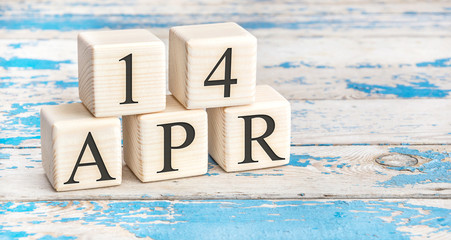 April 14th. Wooden cubes with date of 14 April  on old blue wooden background.